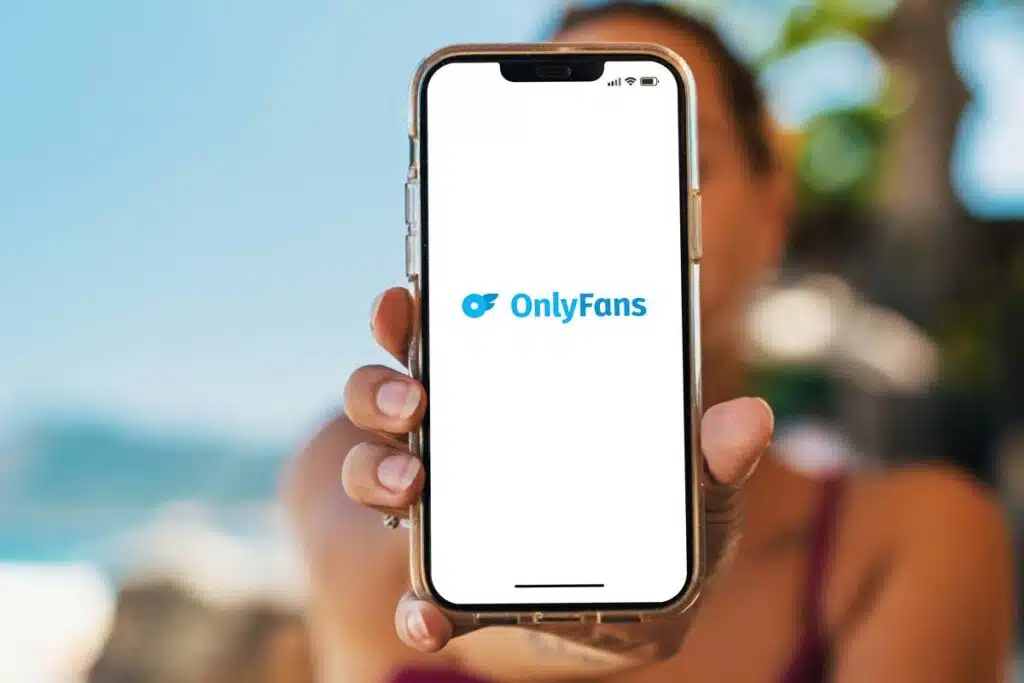 Persona sosteniendo un teléfono móvil con el logo de OnlyFans en la pantalla