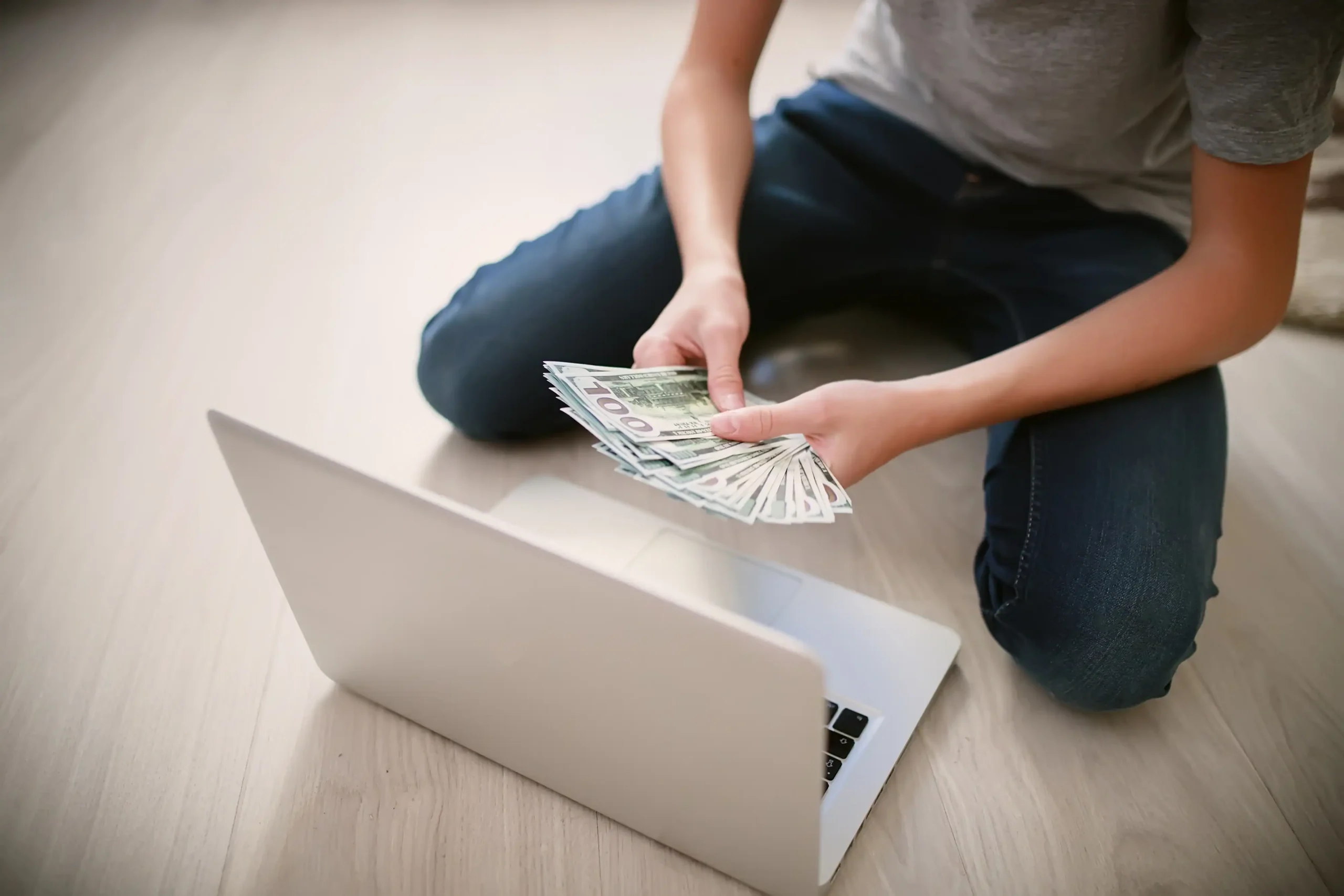 Persona contando dinero frente a una laptop
